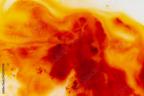 Abstract stains, smudges, drops of orange color on a white milky background