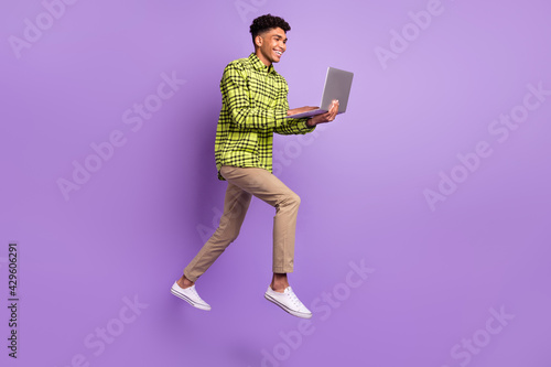 Full length body size of young jumping high using laptop studying isolated on pastel purple color background © deagreez