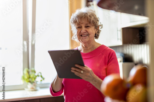 Happy senior woman using digital tablet at home 