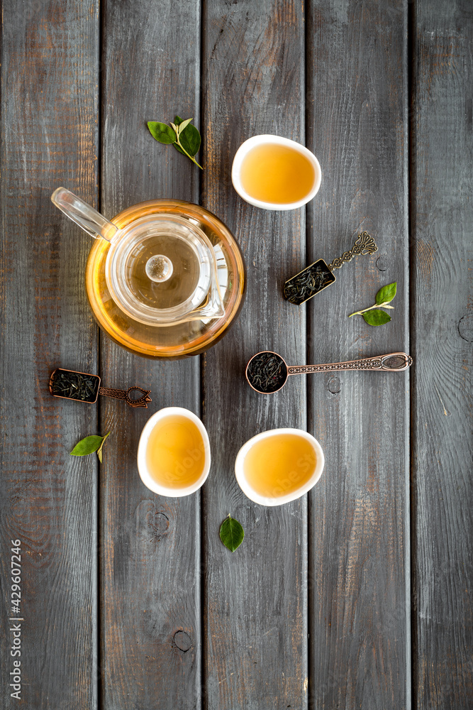 Fototapeta premium Teapot and cups with green tea, top view. Flat lay of tea ceremony concept.