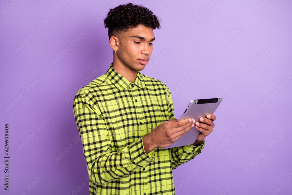 Portrait of handsome focused brunet guy holding in hands using device reading isolated over violet purple color background Portrait of handsome focused brunet guy holding in hands using device reading isolated over violet purple color background
