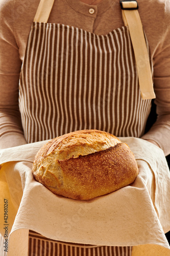 Baker holding loaf of homemade bread