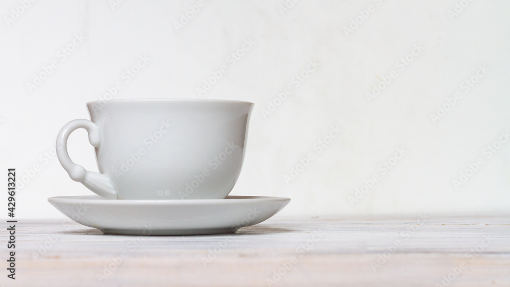 White cup and saucer on a white wooden table, side view White cup and saucer on a white wooden table, side view