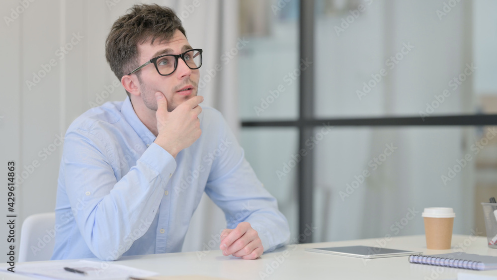 Naklejka premium Young Man Sitting in Office Thinking 