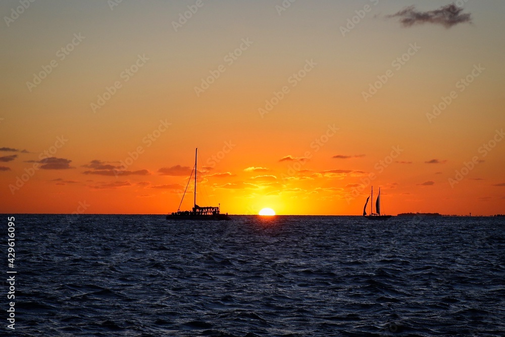 Sunset and sailboat silhouettes on the horizon viewed from Mallory Square, Key West, USA
