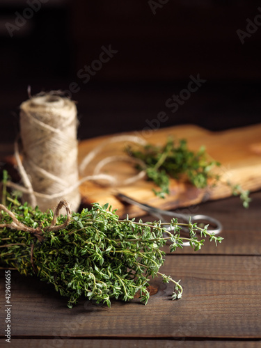 A bunch of thyme on a wooden table with a jute rope.