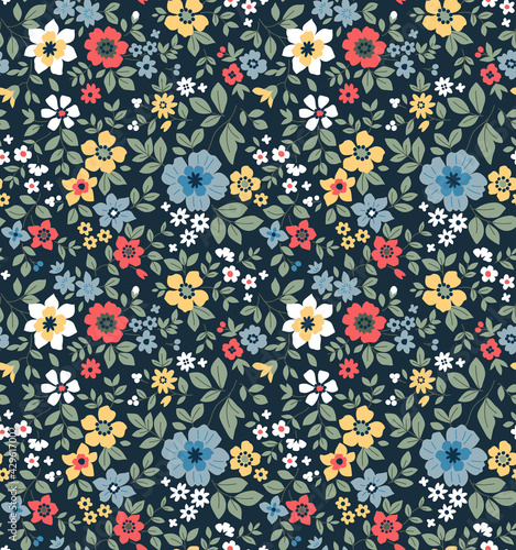 Seamless floral pattern. Ditsy background of small colorful  flowers. Small-scale flowers scattered over a dark blue background. Stock vector for printing on surfaces and web design.