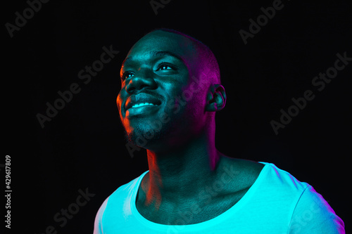 Young happy African-American man isolated on dark background in neon light