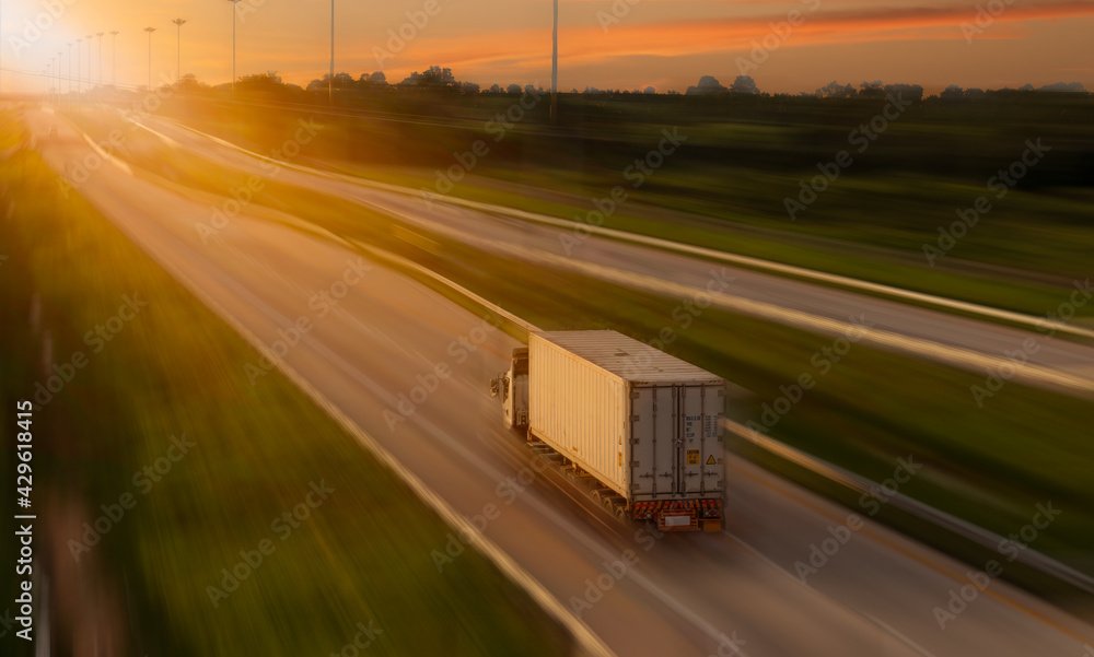 Cargo truck with heavy container speed on high way road to delivery logistic business with sun sky background