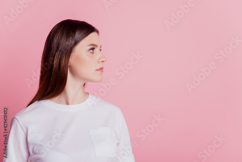 Young calm focused charming girl look empty space on pink background