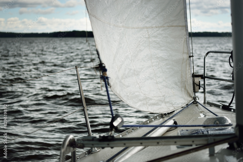 White yacht sailing during the storm. Boat side railing, mast winch ...