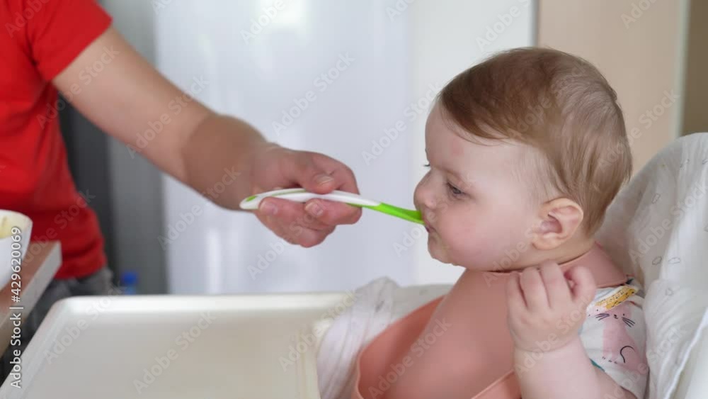 Woman feeds a little girl with a spoon Woman feeds a little girl with a spoon