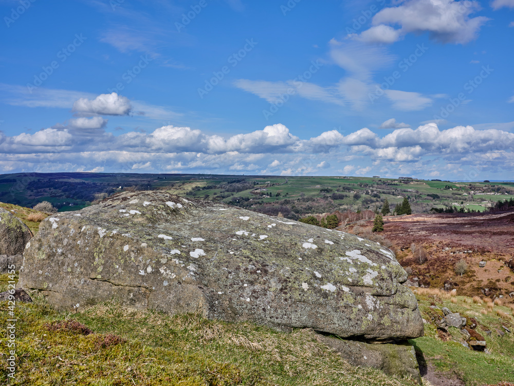A large rock hangs on the edge of a steep moorland valley