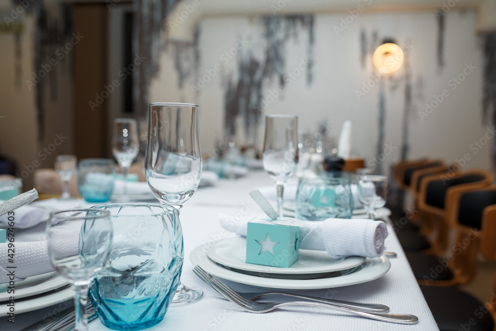 Fototapeta premium Festive table set with white cloth, plates, forks blue glasses and bomboniere for boy happy birthday party.