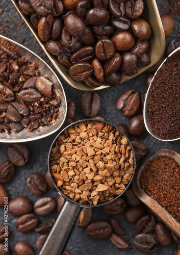 Ground and bean coffee and freeze dried instant coffee granules in various spoons and scoops on black background. Macro