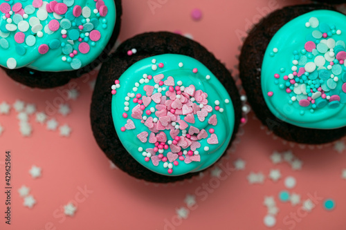 Sugar cupcakes with hearts and frosting close-up on a pastel pink blurred background