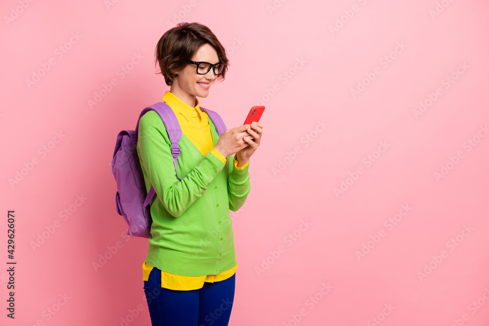 Photo of lady dressed yellow shirt glasses backpack holding looking modern device empty space isolated pink color background Photo of lady dressed yellow shirt glasses backpack holding looking modern device empty space isolated pink color background