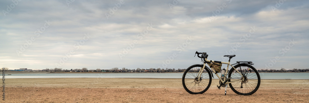 Fototapeta premium spring biking, touring or commuting - bicycle on a lake beach, Boyd Lake State Park in northern Colorado, panoramic banner