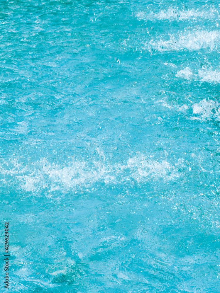 Blue water background with jet splash. Pulsating blue pool water with jets of incoming water. Texture and abstract backgrounds. Blue water background with jet splash. Pulsating blue pool water with jets of incoming water. Texture and abstract backgrounds.