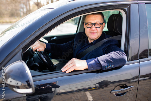 Business trip. Confident senior businessman sitting in car and smiling at camera © F8  \ Suport Ukraine