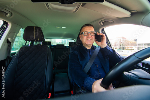 Smiling middle age businessman talking on smartphone in car