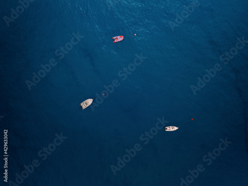 Aerial view of three boats moored offshore and surrounded by a deep blue sea in Caminia, Calabria, Italy. photo