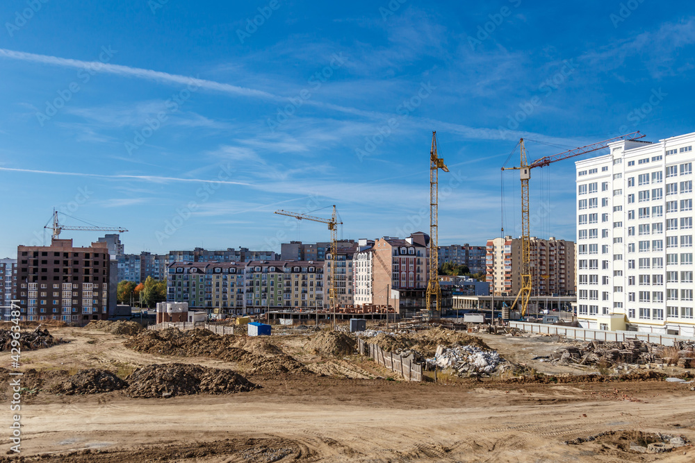 Construction site background. Hoisting cranes and new multi-storey buildings. Industrial background.Building construction site work against blue sky