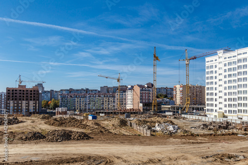 Construction site background. Hoisting cranes and new multi-storey buildings. Industrial background.Building construction site work against blue sky © bukhta79