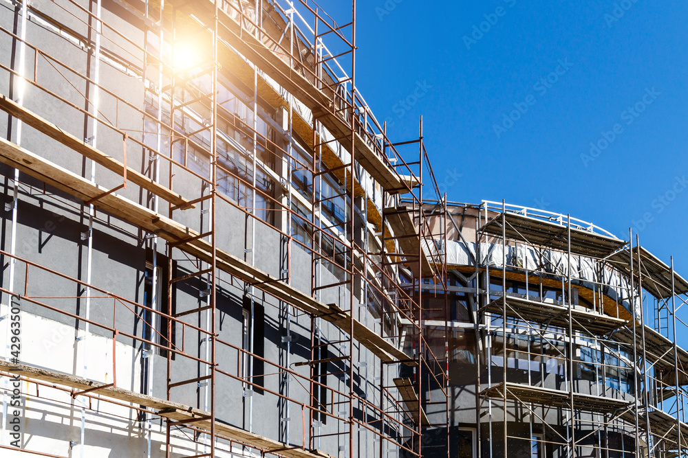 Extensive scaffolding providing platforms for work in progress on a new apartment block,Tall building under construction with scaffolds,Construction Site of New Building