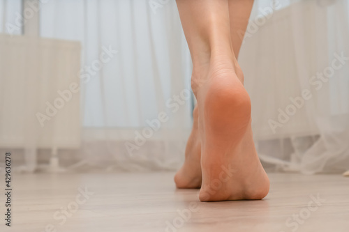 Close-up of a young woman's bare feet on a warm floor in a bedroom or living room. Women's bare feet walk in a room with an electric heated floor in a modern house. Copy space © yaroslav1986