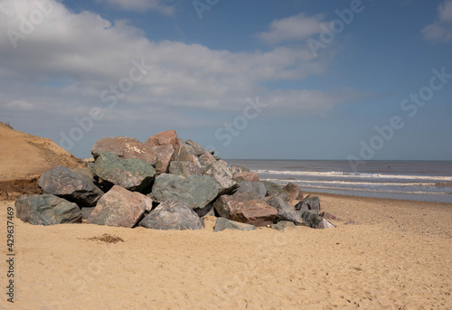A pile of large rocks sitting on a beach being used as a sea defence