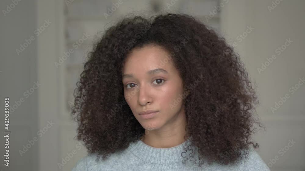 Young american black woman with curly hair, portrait closeup shot. Afro hairstyle, attractive beautiful woman on white blurred background Young american black woman with curly hair, portrait closeup shot. Afro hairstyle, attractive beautiful woman on white blurred background