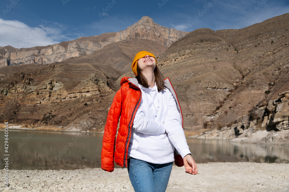 A portrait of a traveler. Women hiking woman happy and smiling, pulling her cap over her eyes and throwing her head back laughs while hiking in the mountains.