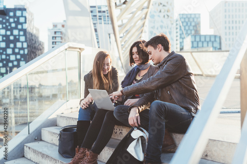 three people sitting outdoor using notebook