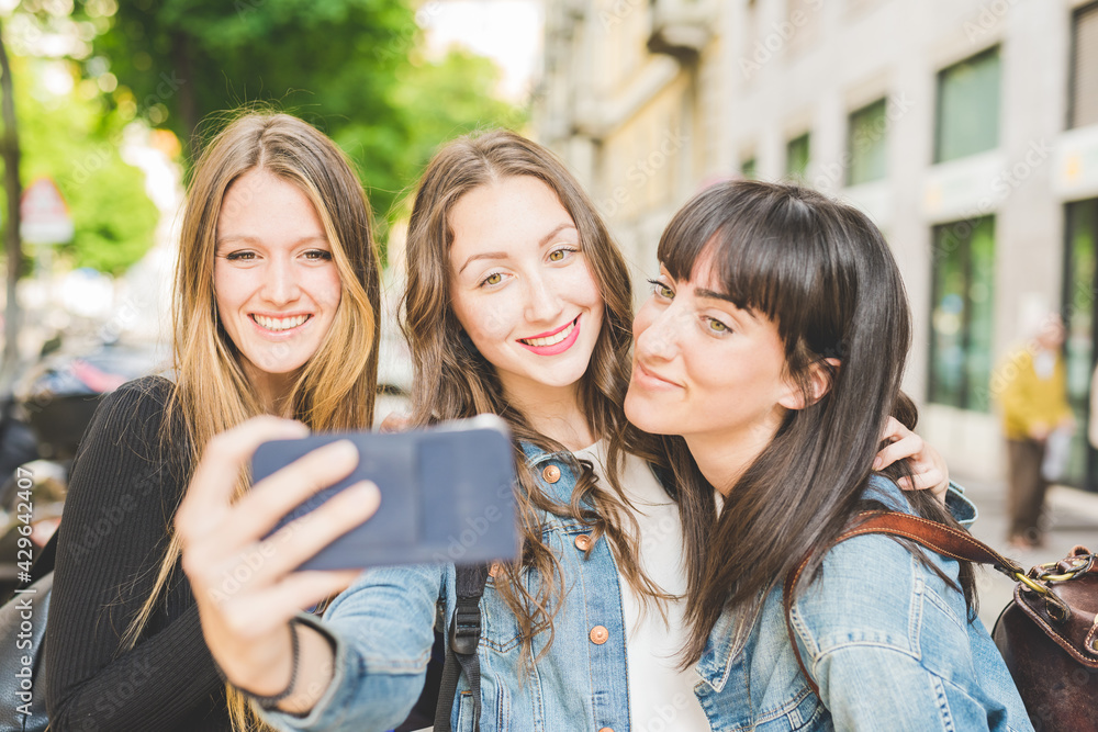 Three young beautiful caucasian young women millennials, taking selfie with smart phone hand hold Three young beautiful caucasian young women millennials, taking selfie with smart phone hand hold