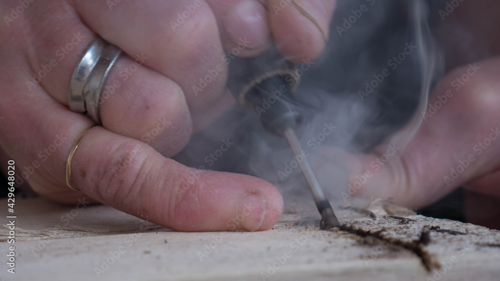 close-up of worker's hand with tools hacking wood with smoke that is seen from overheating of the too close-up of worker's hand with tools hacking wood with smoke that is seen from overheating of the too