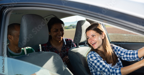 Young adult woman driver talking in car with two friends enjoying road trip © JackF