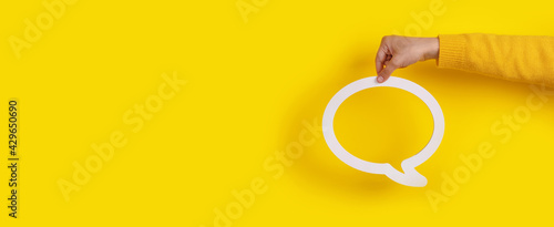 Dialogue bubble in hand over yellow background, panoramic image photo