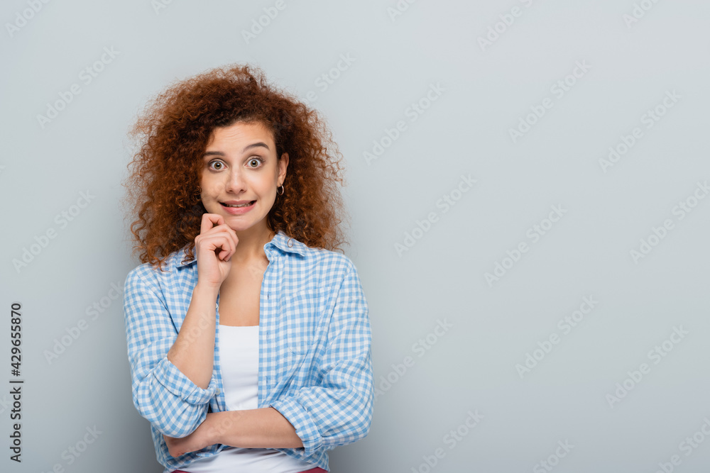 discouraged woman holding hand near face while looking at camera on grey background discouraged woman holding hand near face while looking at camera on grey background
