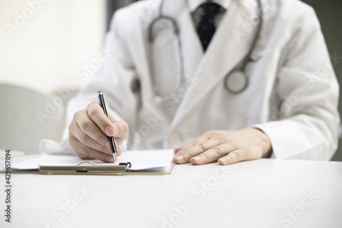 Doctor writing on clipboard in office