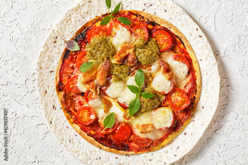 hot pizza with tomatoes, cheese, bacon, pesto