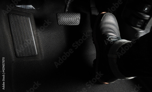 Close up the foot pressing foot pedal of a car to drive. Accelerator and brake pedal in a car. Driver driving the car by pushing accelerator and break pedals of the car. inside vehicle. control pedal.