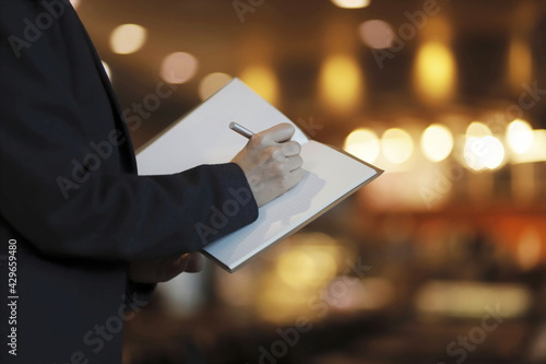Midsection of businesswoman writing on notepad