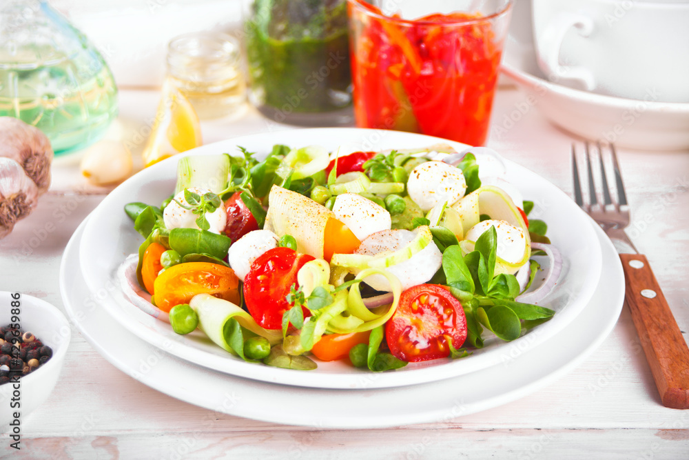 salad of fresh cherry tomatoes, mozzarella, basil, radish and other greens on the dinner table salad of fresh cherry tomatoes, mozzarella, basil, radish and other greens on the dinner table