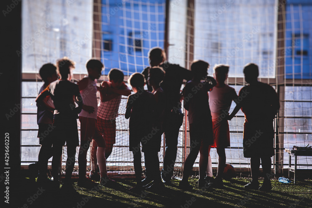 Junior young football team silhouette with a coach, group of kids children soccer team having training with trainer instructor, soccer or football coach