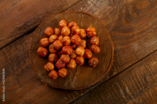 Hazelnuts scattered on a wooden round board.
