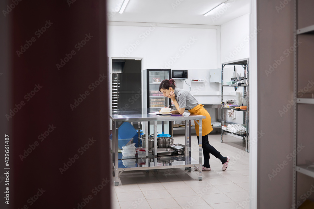 The pastry chef girl makes notes in a notebook The pastry chef girl makes notes in a notebook