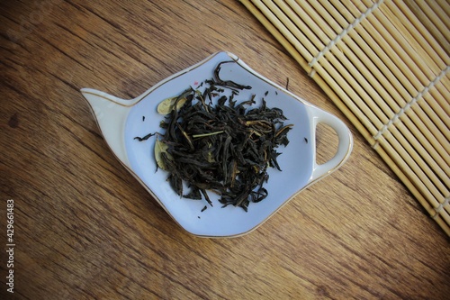 atmosphere Loose dried black tea leaves on plate on wooden background with bamboo