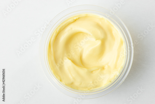 Top view on a cup of cheese sauce on white background