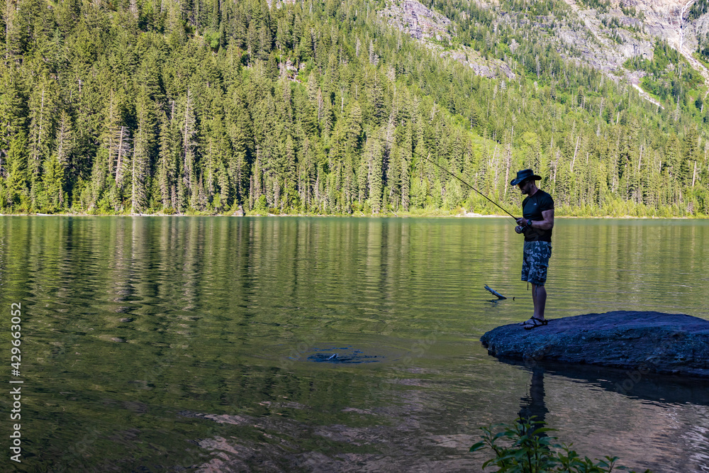 Fisherman at Avalanche Lake and surrounding mountain range at Glacier National Park